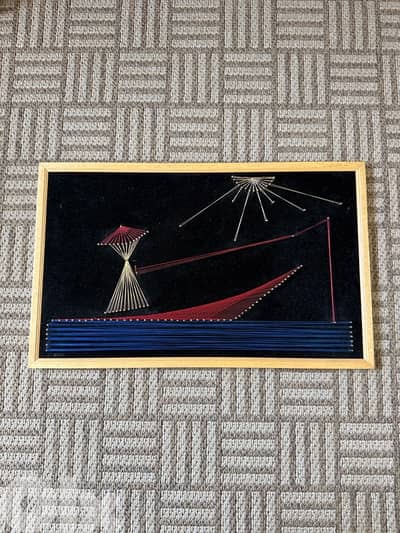 Vintage handmade string art wall decor on black velvet background